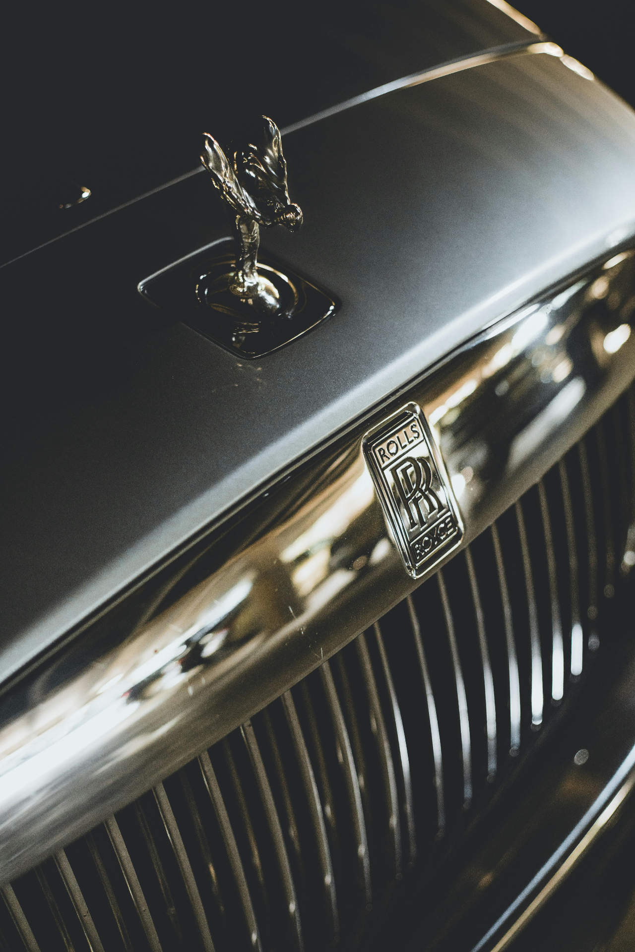 Close-up of a Rolls-Royce Spirit of Ecstasy hood ornament and chrome grille — discreet luxury